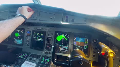 first person view of a pilot adjusting the buttons in the cockpit of an airplane