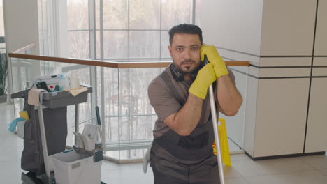 arabic cleaning man posing at camera while holding a mop stick