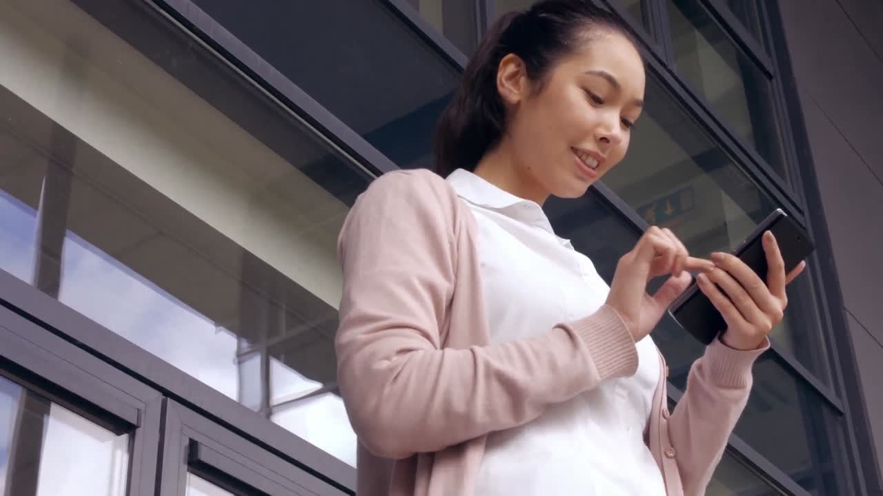 아시아 사업가 여성 이 밖 에서 전화 를 사용 하고 있다