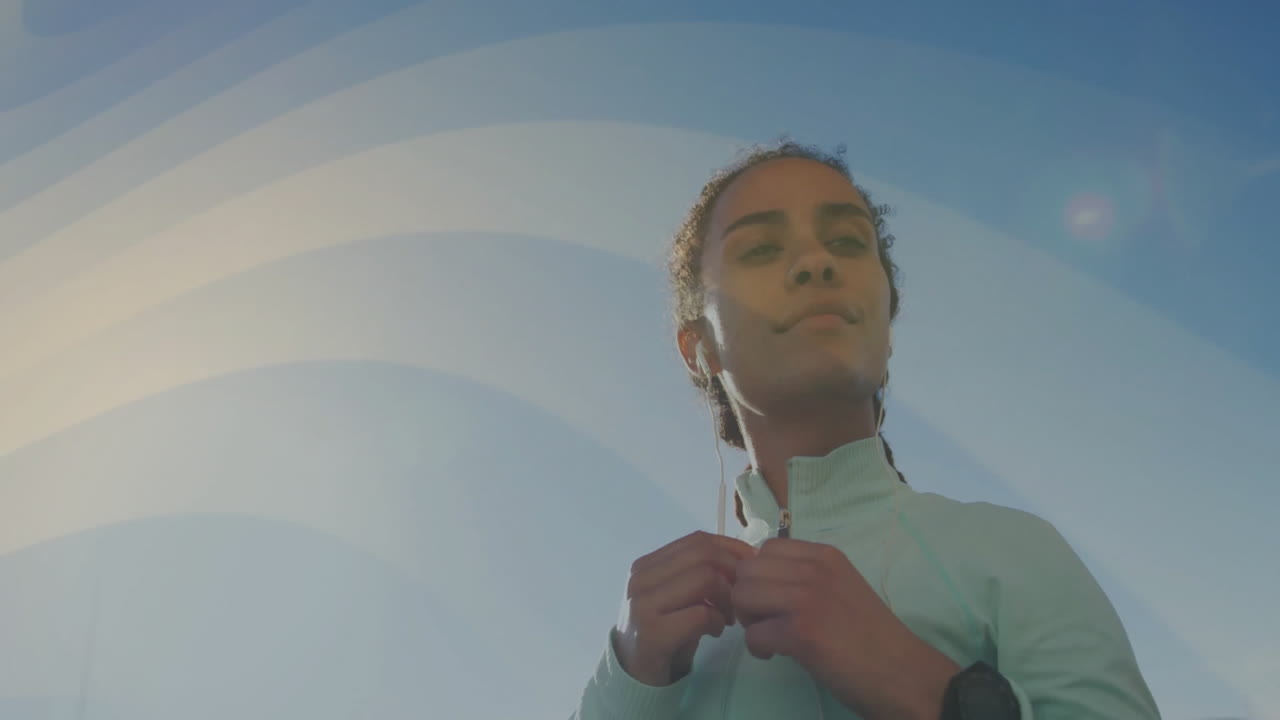 Woman adjusting jacket zipper outdoors, showing smartwatch data overlay and fitness chart animation