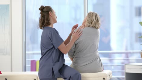 caucasian female physiotherapist stretching neck of female senior patient at rehab center