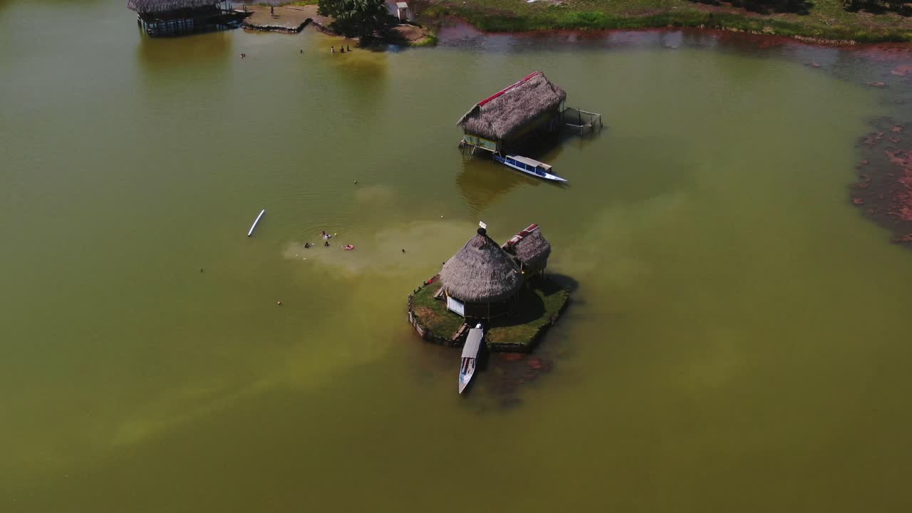 video de drones aéreos diurnos de 4k mirando una pequeña casa construida sobre el agua con un bote estacionado en la laguna de los milagros, tingo maria, perú