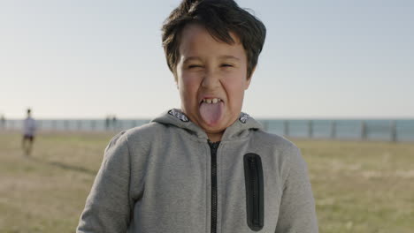 portrait of happy hispanic boy playing making faces funny silly enjoying sunny day at seaside park