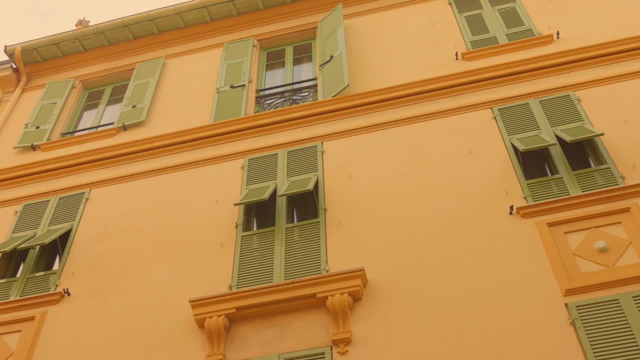 Facciata di edificio tradizionale con molteplici finestre adornate con persiane di legno verde chiaro a Monaco. - Inquadratura dal basso.
