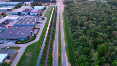 dutch scenic nature road. a wide roadway through the netherlands lined with trees, showcasing commercial buildings and lush greenery nearby