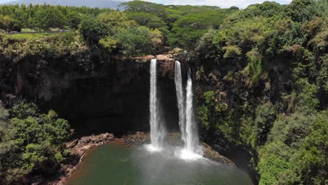 version one. aerial orbit of wailua falls and wailua state park, surrounded by forest jungle and trees.