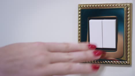 mano de mujer apagando la luz en la pared blanca en el interior de la habitación acogedora