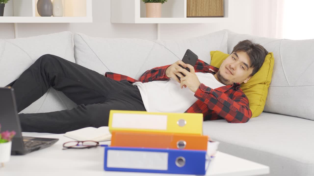 Lazy man laughing at phone in hand and not doing his job.