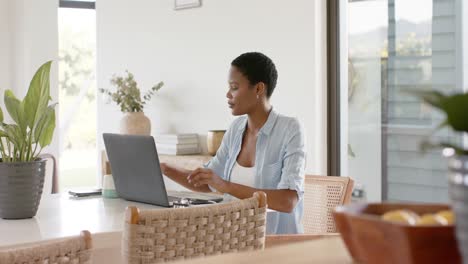 mujer afroamericana sentada a la mesa y usando computadora portátil, cámara lenta
