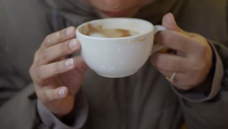 person drinking coffee from a white cup