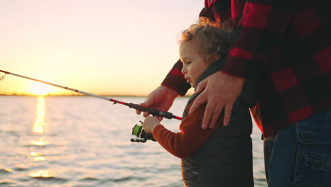 niño caucásico rizado está aprendiendo a pescar padre o abuelo le está enseñando familia feliz
