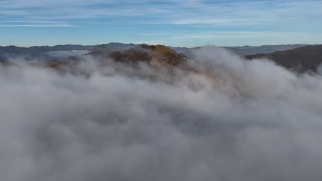 mountain peaks emerging from dense cloud inversion below blue sky