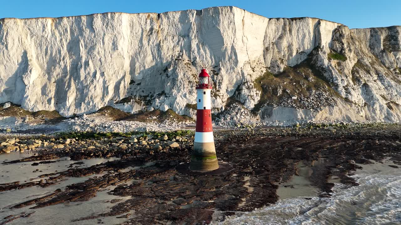 Aerial footage of beautiful red and white Lighthouse, white cliffs, and rocky coastline. Smooth pull-away shot revealing stunning coastal views. Ideal for travel, nature, and landscape projects.