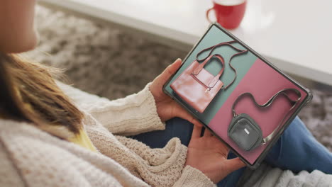 caucasian woman using tablet at home for online shopping, bags on screen, slow motion