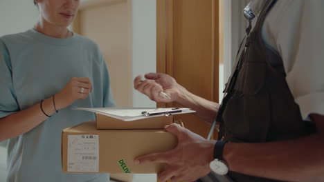 girl signing document and taking parcels from courier
