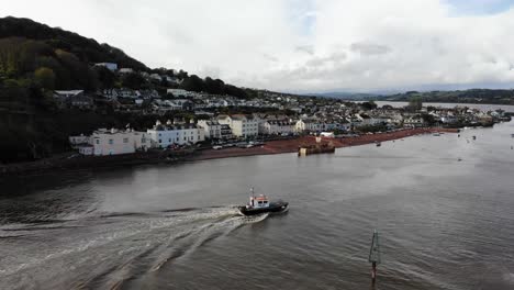 Kleines-Trawlerboot,-Das-Im-Fluss-Teign-Mit-Shaldon-Beach-Im-Hintergrund-Ankommt