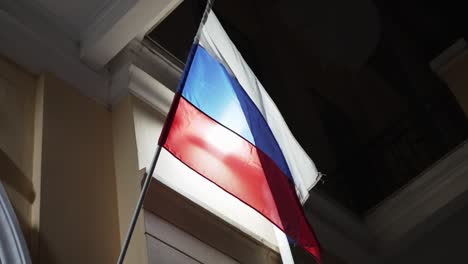 flag of russian federation develops in wind at night on administrative building.
