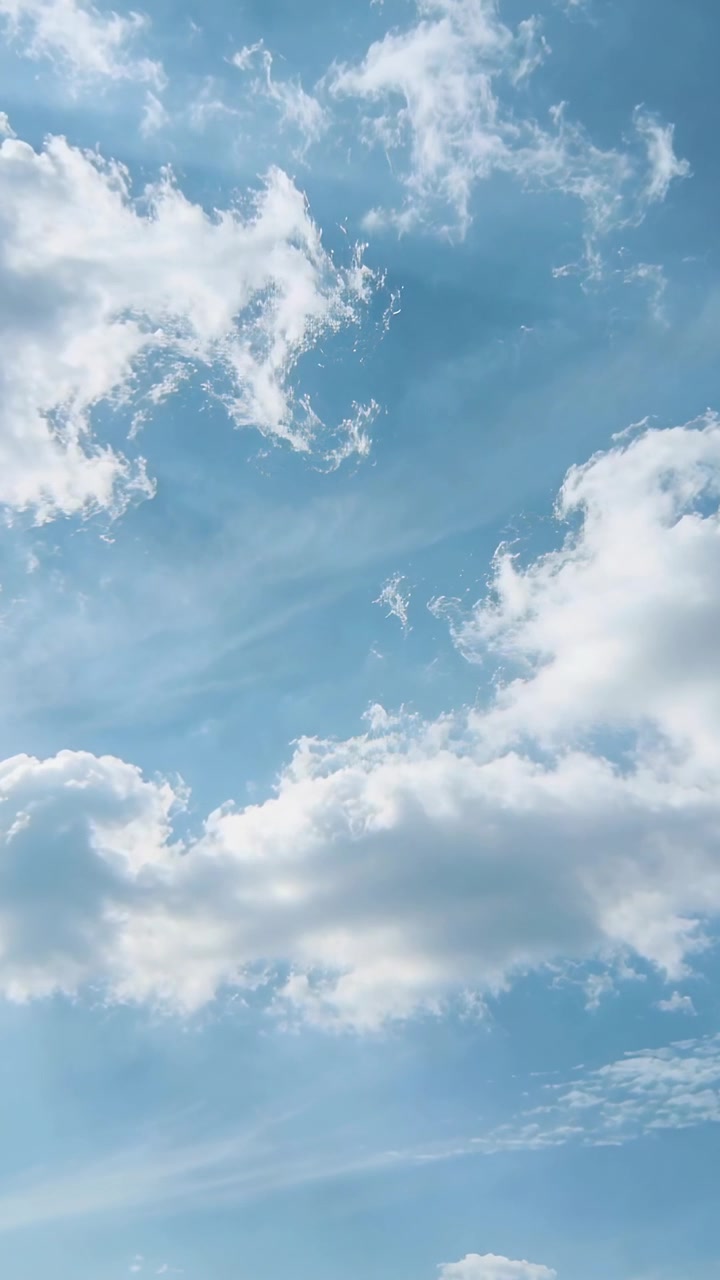 Blå himmel med spredte cumulusskyer og tynde skyer, der driver hen over en vertikal portrætramme