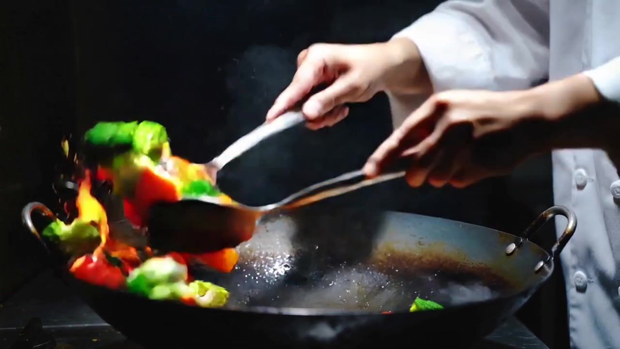 Flame sparking hands in chef jacket scooping and tossing to sear vegetables over wok, spatula ladle