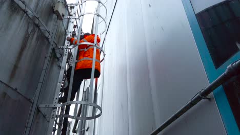 factory worker climbing down industrial ladder in a chemical plant in norfolk, england - low angle static shot