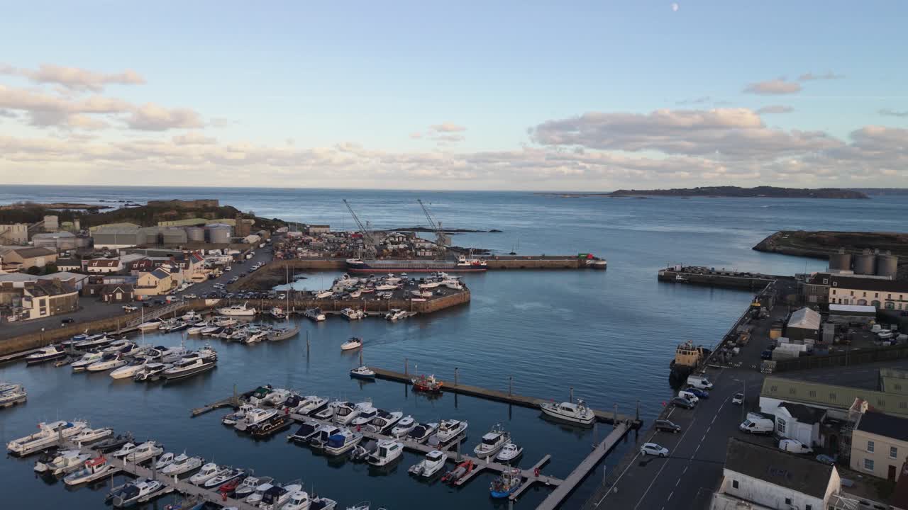 Le riprese da drone di St. Sampson, Guernsey, mostrano il porto con una nave in banchina nella marina e il Southside al tramonto, con il Castello di Vale, Herm e il Canale di Little Russell sullo sfondo.