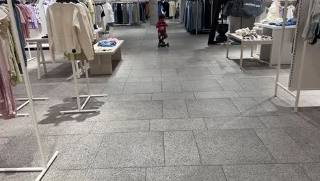 3-year-old black toddler happy and funny riding a skate inside a shop