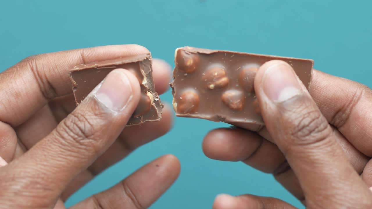 persona sosteniendo una barra de chocolate rota con avellanas