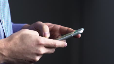 close up side ways shot of a man typing on cellphone, fingers on touch screen