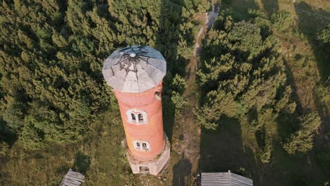 fast aerial drone flight towards and over lost place lighthouse with zoom in at the coast of baltic sea - estonia in europe - nature helicopter flyover establishing shot summer 2022 - bird view