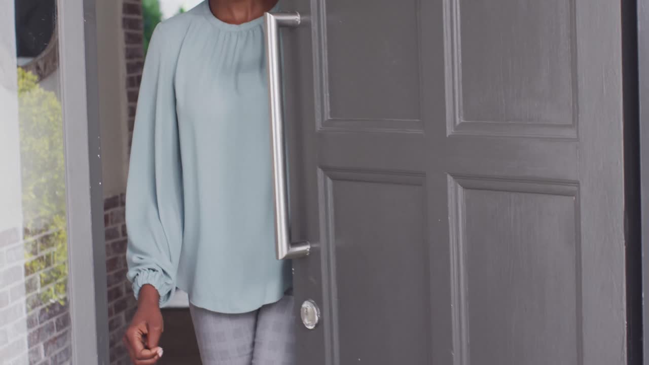 Portrait of happy african american woman at door