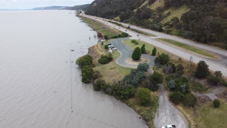 Dron-Ascendiendo-Cerca-De-Un-Lago-Y-Una-Autopista-De-4-Carriles-Que-Muestra-Una-Zona-De-Descanso-Y-Una-Montaña