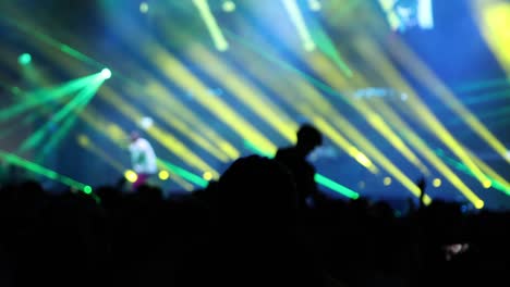 flashing lights on concert stage at night show with singer performance and fans silhouettes