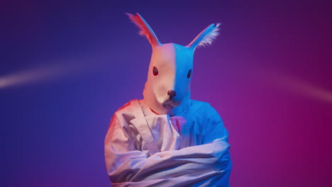 person in bunny mask and straight jacket under neon lights