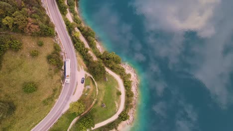 Luftaufnahme-Des-Ledrosees-Aus-Der-Vogelperspektive-Mit-Einer-Straße-Und-Einem-Vorbeifahrenden-Auto-Und-LKW