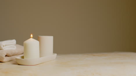 Still-Life-Of-Lit-Candle-And-Soft-Towels-As-Part-Of-Relaxing-Spa-Day-Decor