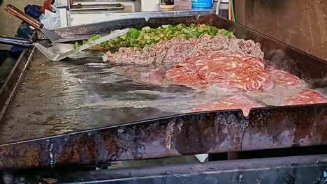 close up raw meat on hotplate griddle sizzling with grease and fat seeping out and smoke rising