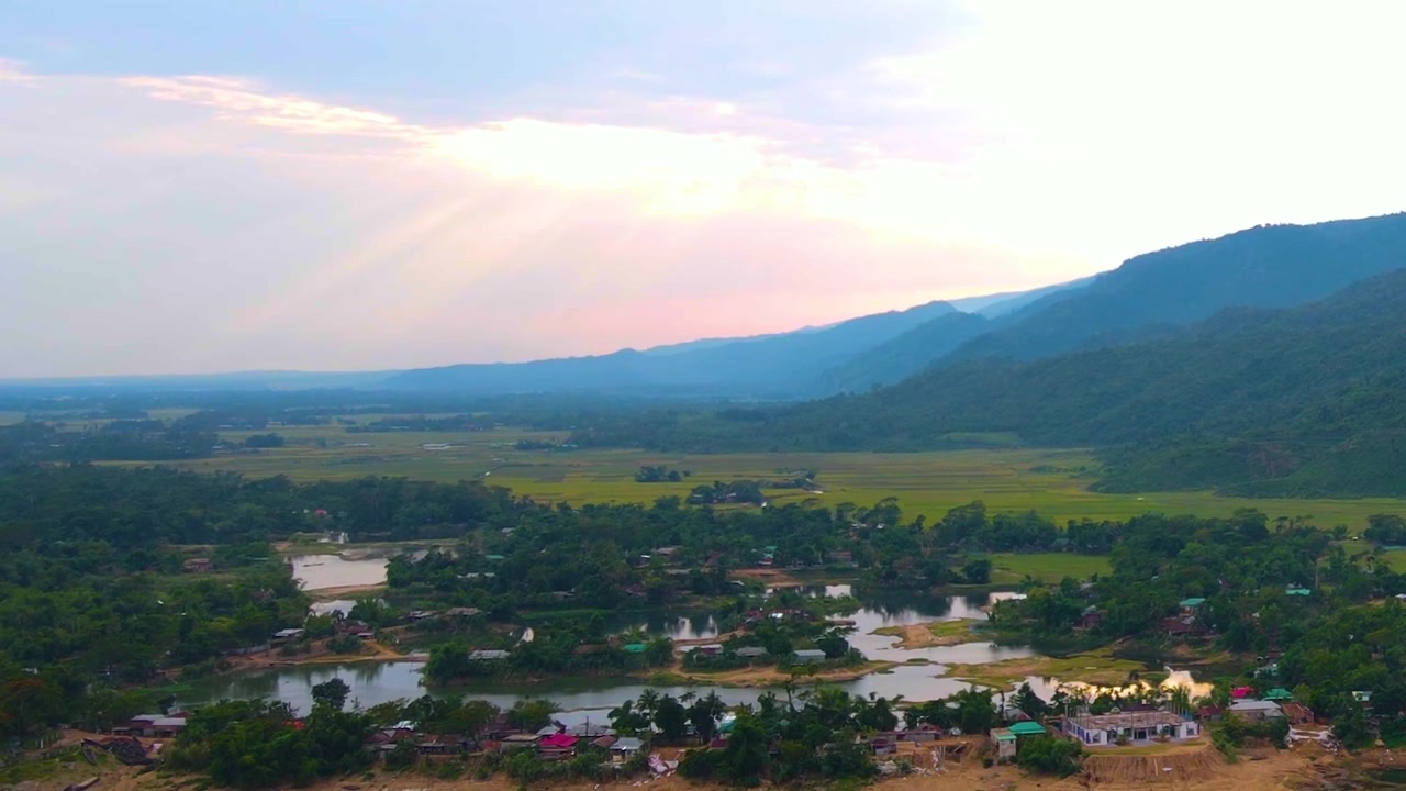 Luz solar surgindo sobre uma vila tranquila com lagoas e lagos ao longo de colinas na Ásia, vista aérea
