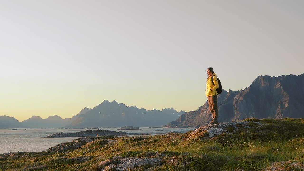 mujer viajera relajándose y disfrutando de la vista de un paisaje noruego desde una colina.