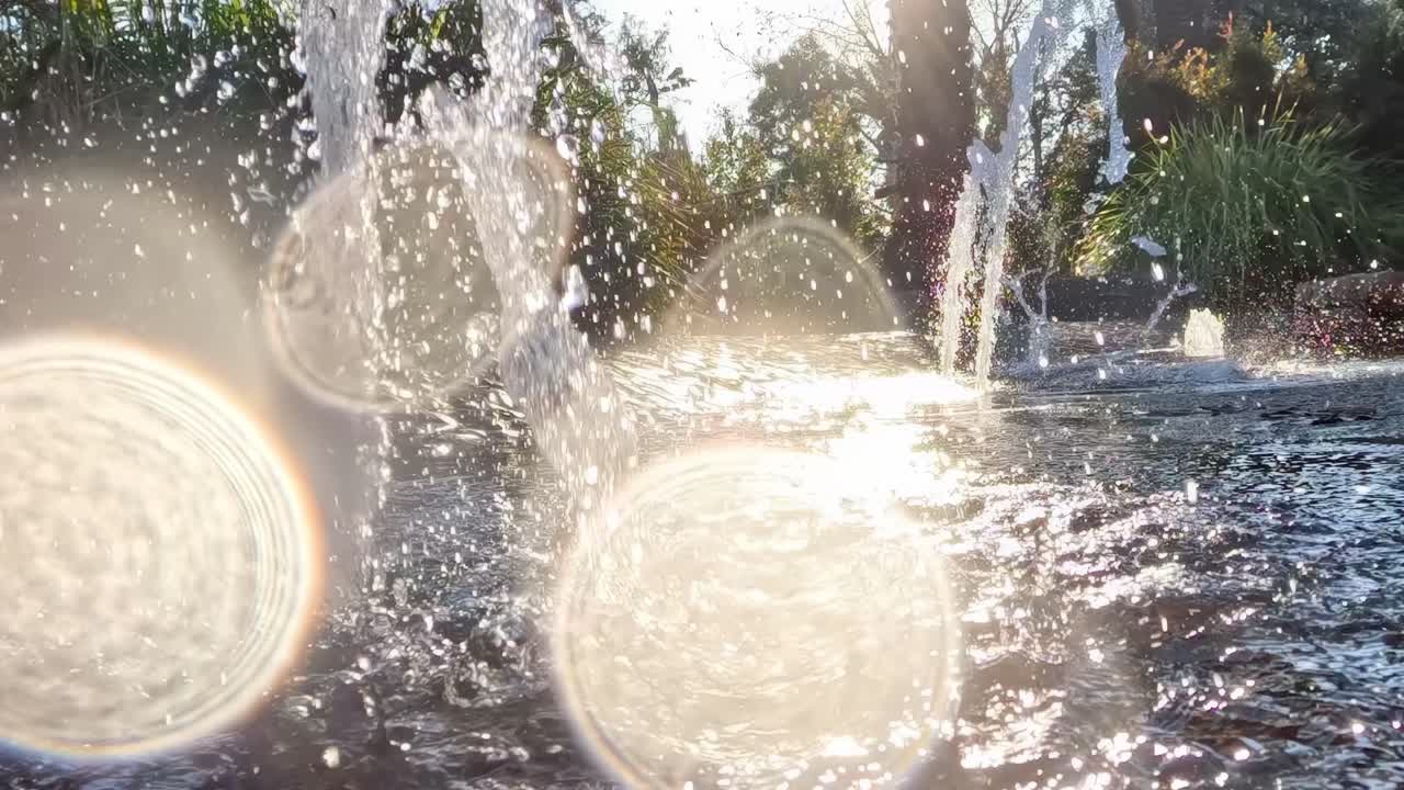Close-up of water droplets splashing in sunlight, creating a sparkling effect with lens flares.