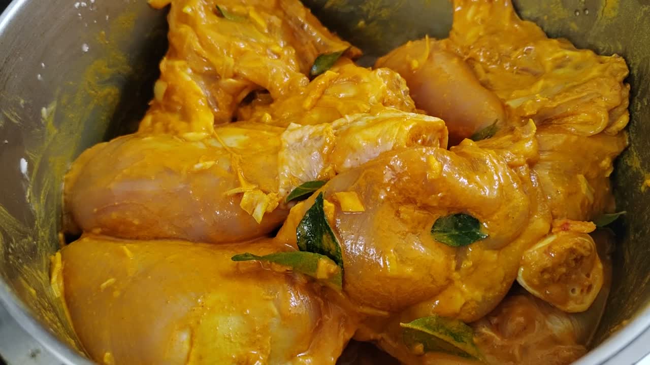 Marinated raw chicken pieces infused with rich spices, ready to be cooked to perfection, releasing an irresistible aroma and flavor.