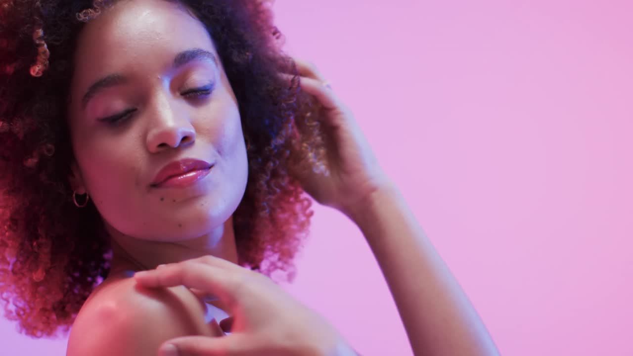 mujer biracial con cabello oscuro en luz azul y rosa, cámara lenta