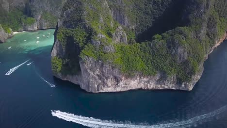 aerial drone footage of speedboats, boats and yachts circling a island in portugal during the summer time while the sun is shining in 4k resolution