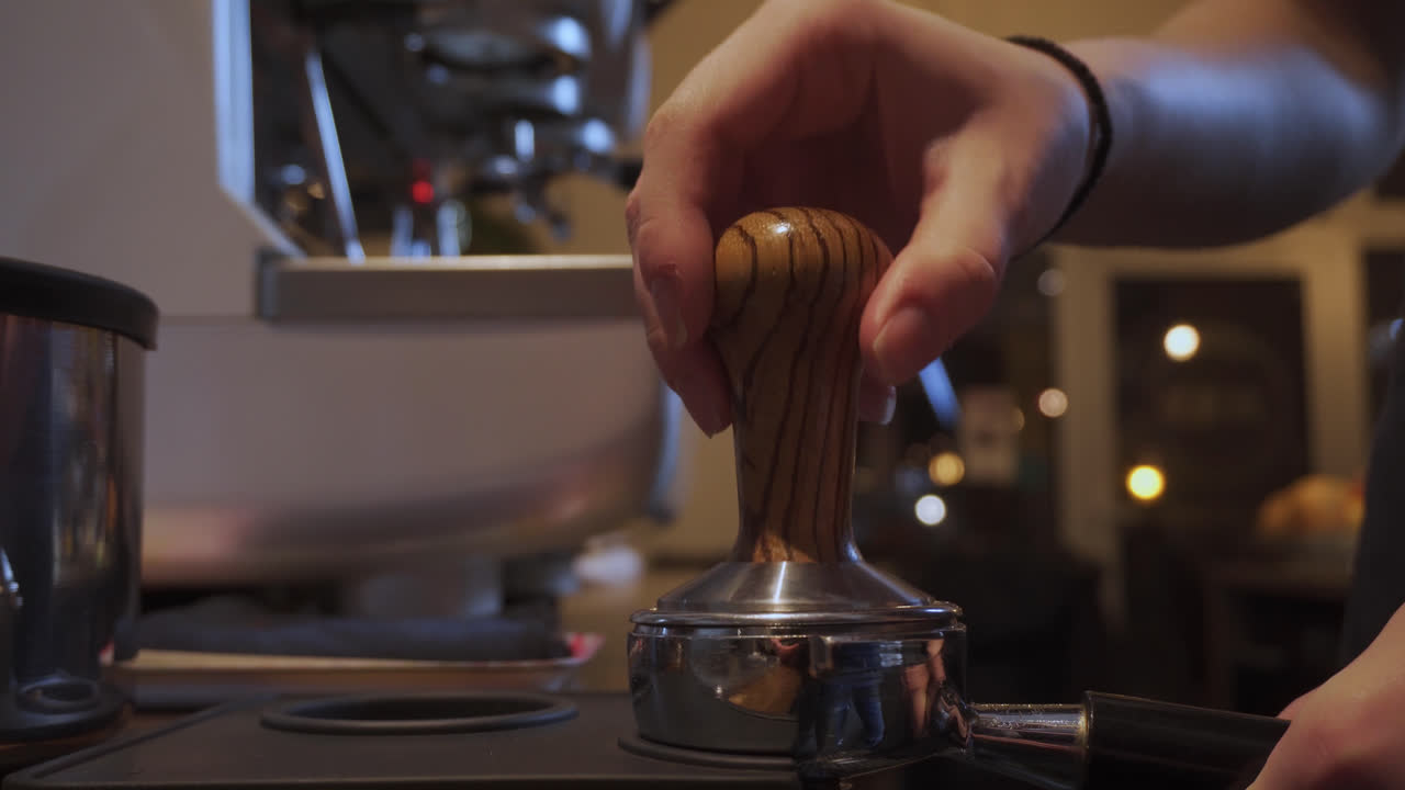 Barista che pressa il caffè macinato all'interno di un piccolo bar scarsamente illuminato