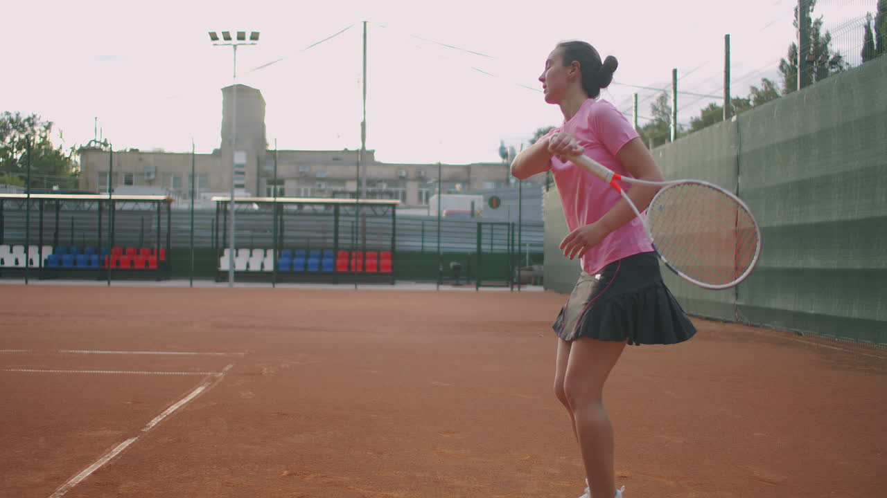 천천히 공을 돌려주는 코트에서 테니스를 하는 젊은 백인 여성