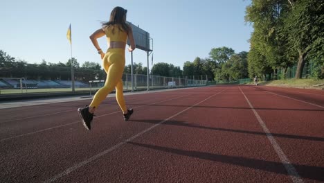 frau joggt auf einer außenstrecke in sportbekleidung auf einem sportplatz