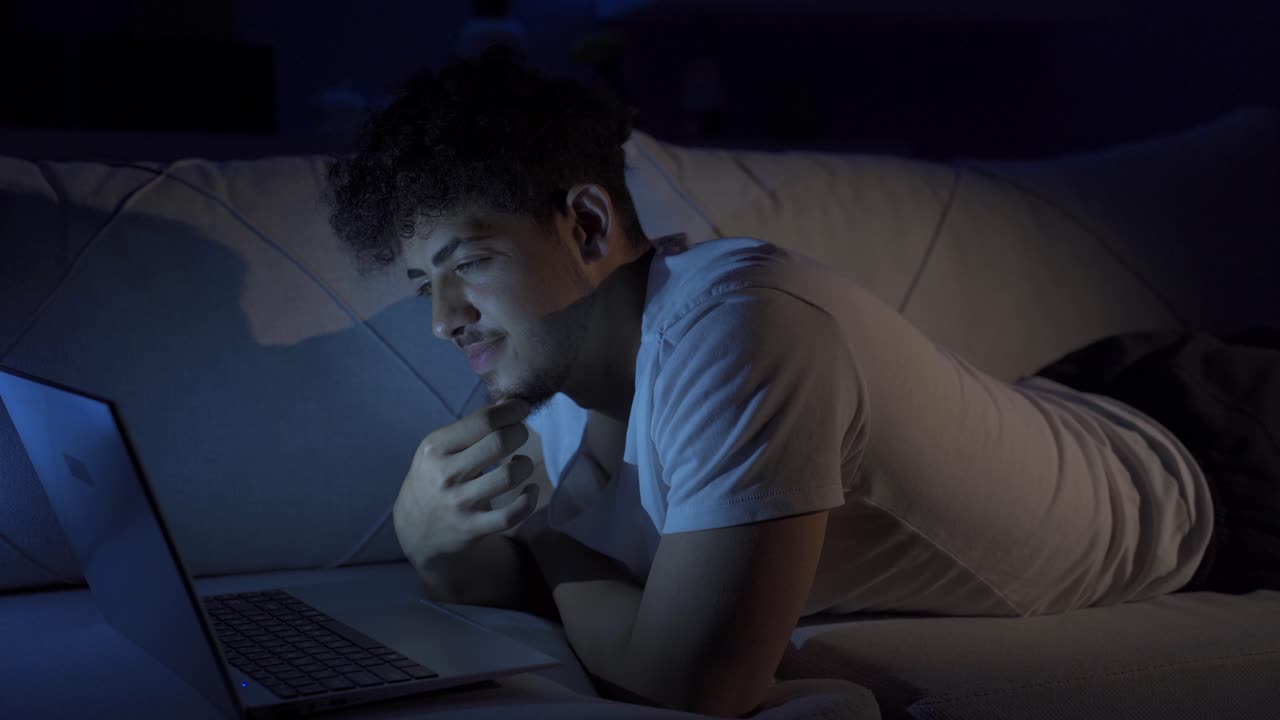 행복하고 유쾌한 젊은이가 노트북에서 영화를 보고 있습니다.