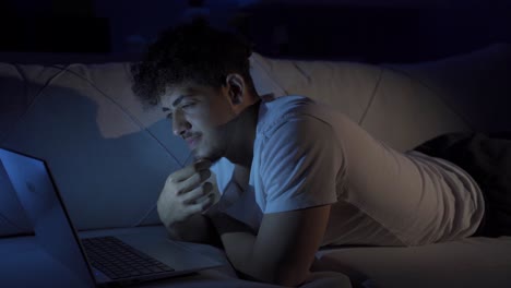 happy and cheerful young man watching movie on laptop.