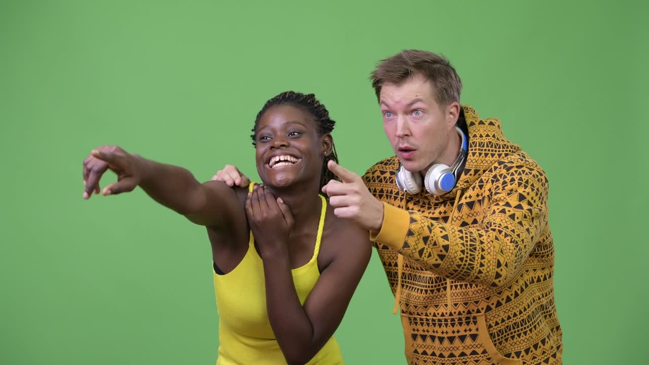 Young multi-ethnic couple pointing finger together