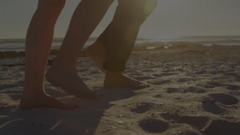animation of light spots over caucasian couple walking on beach