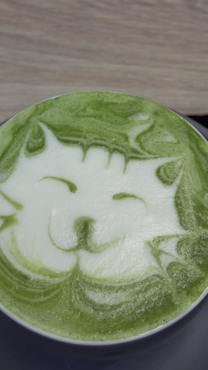 Close up of a kitten latte art on a matcha latte. Vertical
